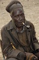 Assis, le regard perdu, fumant la pipe, il assiste à un conseil qui s'est réuni dans le cadre de futurs élections.
Le KAOKOLAND est divisé en plusieurs district ayant chacun à sa tête un chef de clan. Vieux Chef Himba; KAOKOLAND . NAMIBIE. 
