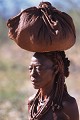 Tous les objets de la vie quotidienne, ustensiles de cuisine et bijoux sont réunis dans un panier protégé d'un tissus. 
Il sera porté sur la tête comme dans tous les pays africains. Femme Himba.Portage d'obet sur la tête. KAOKOLAND. NAMIBIE. 